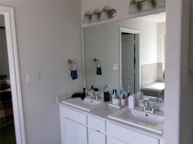 ensuite bathroom featuring double vanity, a tub, a sink, and ensuite bathroom