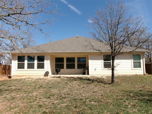 rear view of house with fence and a yard