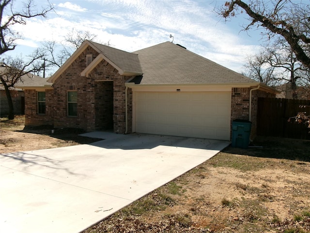 single story home with an attached garage, brick siding, fence, concrete driveway, and roof with shingles