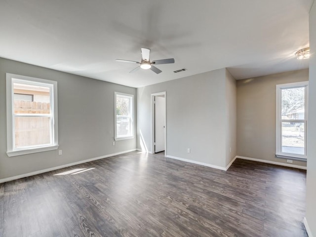 spare room with baseboards, visible vents, ceiling fan, and dark wood-type flooring