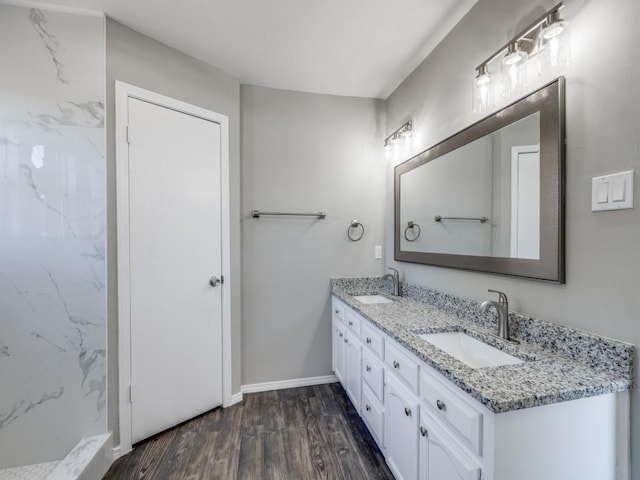 bathroom featuring double vanity, a sink, baseboards, and wood finished floors