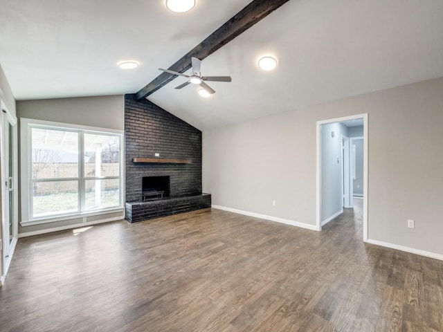 unfurnished living room featuring lofted ceiling with beams, a brick fireplace, wood finished floors, and baseboards