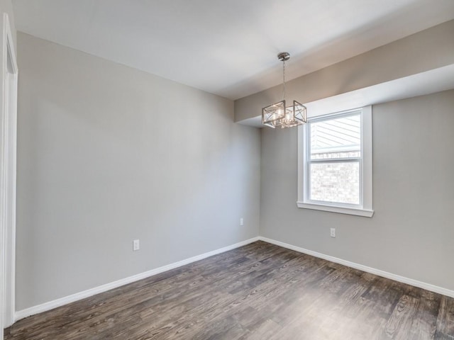 spare room featuring an inviting chandelier, baseboards, and dark wood-type flooring