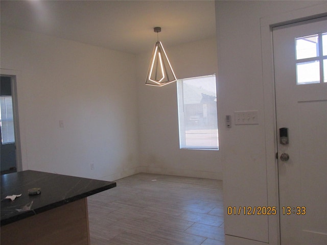 unfurnished dining area featuring light wood-style floors and baseboards