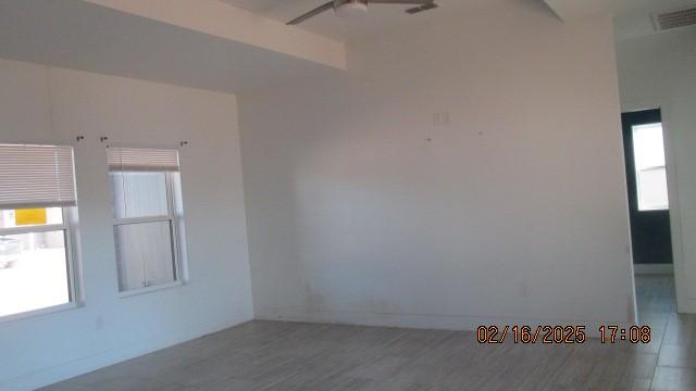 unfurnished room featuring ceiling fan, visible vents, plenty of natural light, and wood finished floors