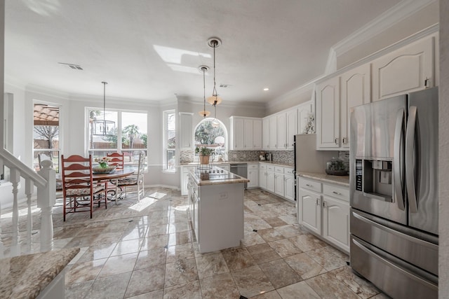 kitchen with tasteful backsplash, white cabinets, appliances with stainless steel finishes, a center island, and crown molding