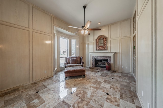 unfurnished room featuring a ceiling fan, a fireplace, and a decorative wall