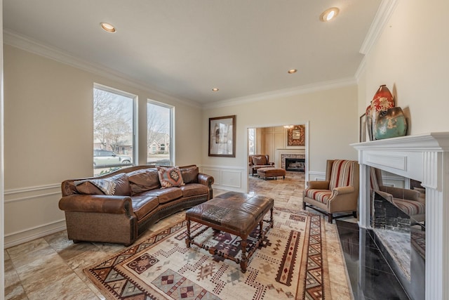 living room with recessed lighting, a wainscoted wall, a decorative wall, a fireplace, and crown molding