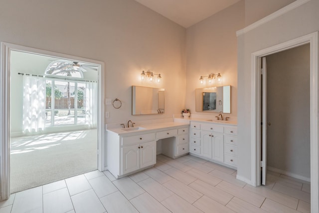 bathroom with double vanity, a high ceiling, a sink, and a ceiling fan