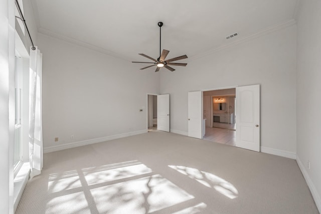 unfurnished bedroom featuring crown molding, visible vents, a towering ceiling, light carpet, and baseboards