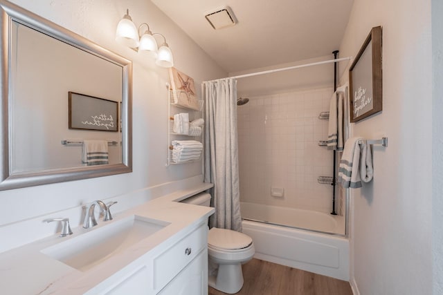 bathroom with shower / tub combo with curtain, visible vents, toilet, vanity, and wood finished floors