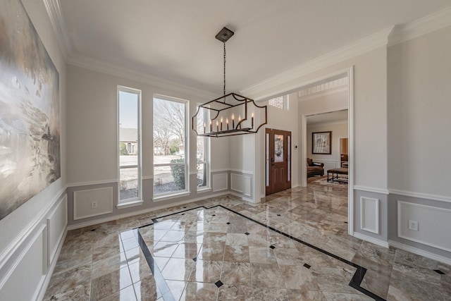 unfurnished dining area with a wainscoted wall, ornamental molding, marble finish floor, a decorative wall, and a notable chandelier