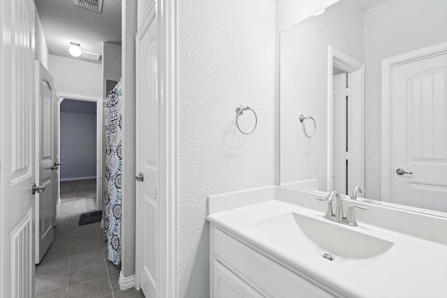 full bathroom featuring tile patterned floors, visible vents, a textured wall, and vanity