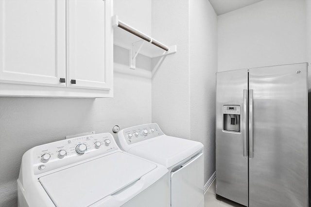 washroom featuring independent washer and dryer, a textured wall, and cabinet space
