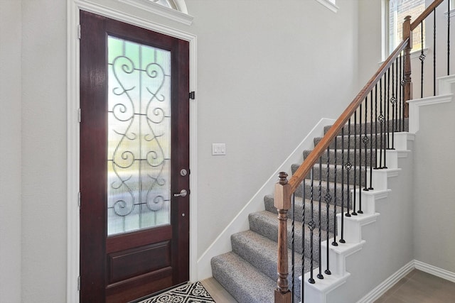 foyer featuring stairway and baseboards