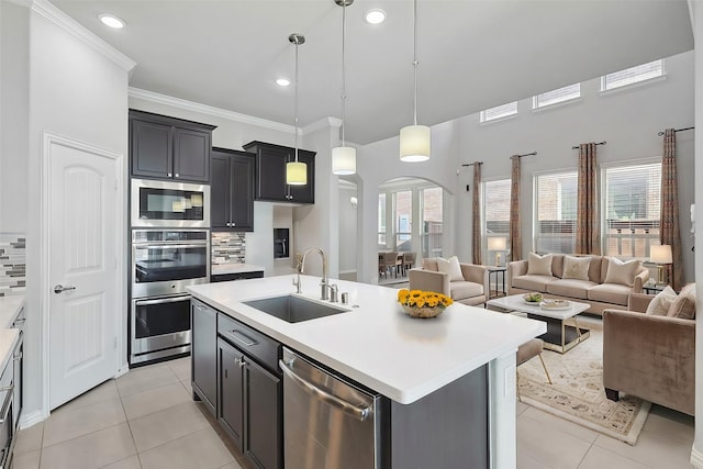 kitchen with arched walkways, appliances with stainless steel finishes, a sink, light tile patterned floors, and open floor plan