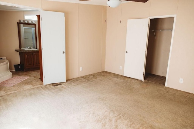 unfurnished bedroom featuring carpet floors, a closet, a ceiling fan, and connected bathroom