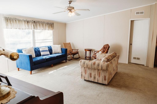 living area with light carpet, visible vents, a ceiling fan, and ornamental molding