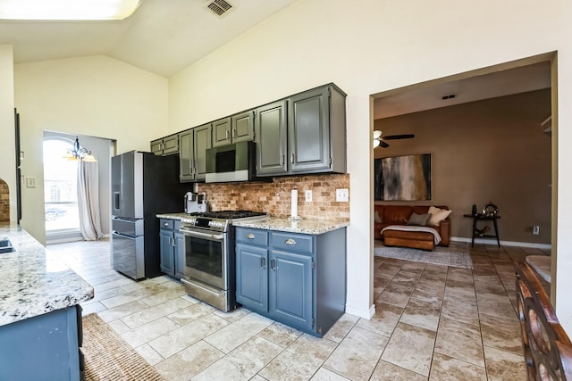 kitchen with light stone counters, visible vents, appliances with stainless steel finishes, high vaulted ceiling, and ceiling fan with notable chandelier