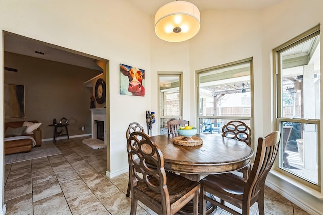 dining room with a fireplace with raised hearth and baseboards