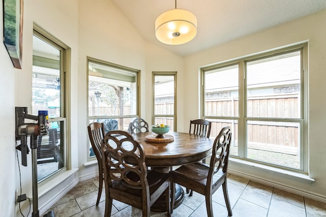 dining room featuring vaulted ceiling, light tile patterned floors, and baseboards