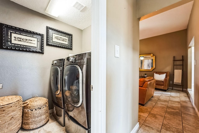 laundry room with a textured ceiling, washer and dryer, laundry area, baseboards, and tile patterned floors