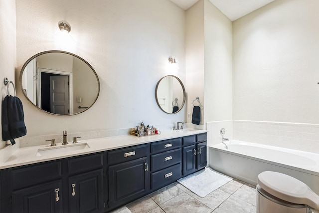 bathroom with double vanity, tile patterned floors, a sink, and a bath