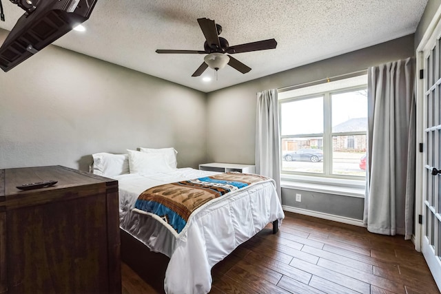 bedroom with dark wood-style floors, ceiling fan, a textured ceiling, and baseboards