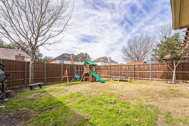 view of yard with a trampoline, a playground, and a fenced backyard