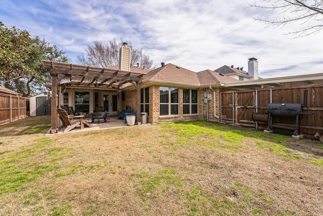 rear view of house with a patio, a fenced backyard, an outdoor structure, a storage unit, and a chimney