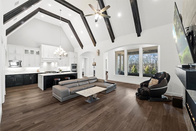 living area featuring high vaulted ceiling, ceiling fan with notable chandelier, baseboards, dark wood-style floors, and beamed ceiling