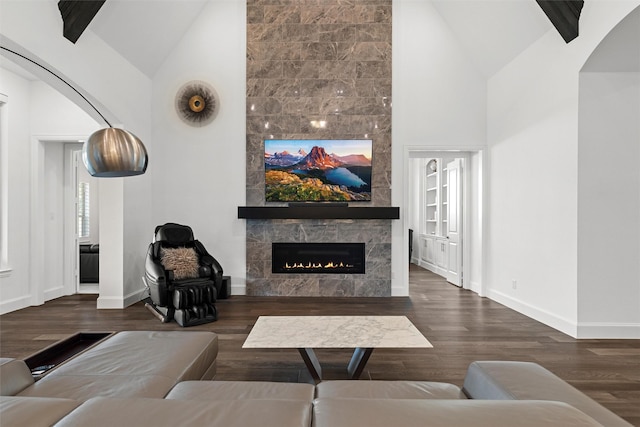 living area featuring high vaulted ceiling, a tile fireplace, baseboards, and wood finished floors