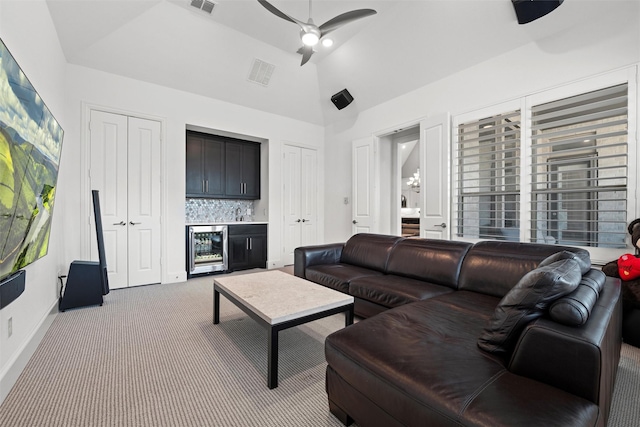 living area with beverage cooler, a ceiling fan, carpet, vaulted ceiling, and a bar