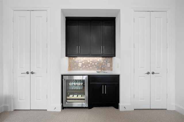 bar featuring wine cooler, indoor wet bar, light colored carpet, backsplash, and a sink