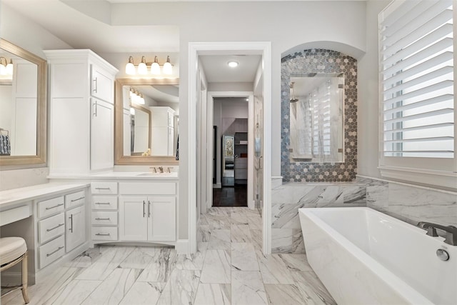 full bath with marble finish floor, a soaking tub, and vanity