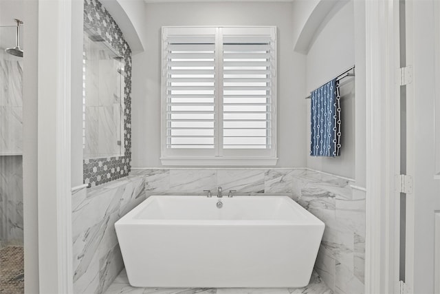 bathroom featuring a marble finish shower, wainscoting, marble finish floor, a freestanding tub, and tile walls