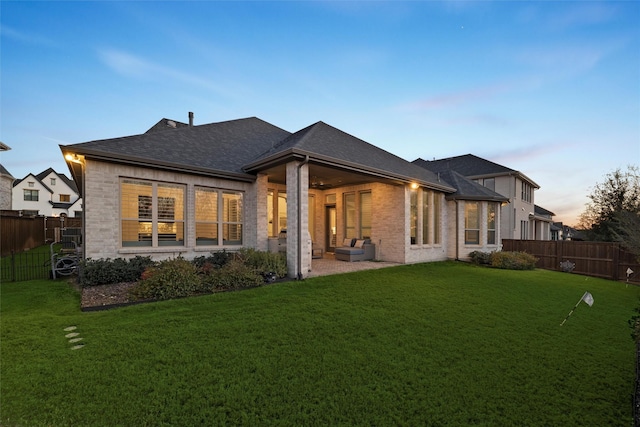 rear view of house with brick siding, a lawn, a patio area, and a fenced backyard