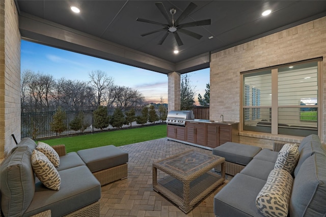 view of patio with grilling area, an outdoor kitchen, an outdoor hangout area, a sink, and a fenced backyard