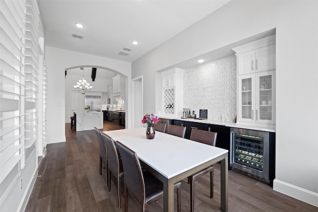 dining room with dark wood-style floors, beverage cooler, visible vents, and arched walkways