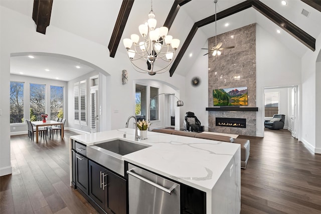 kitchen featuring open floor plan, stainless steel dishwasher, a tiled fireplace, and a sink