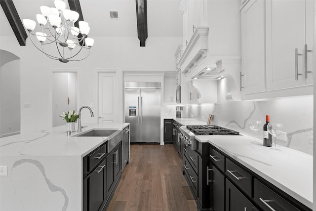 kitchen with dark cabinets, a sink, visible vents, appliances with stainless steel finishes, and beam ceiling