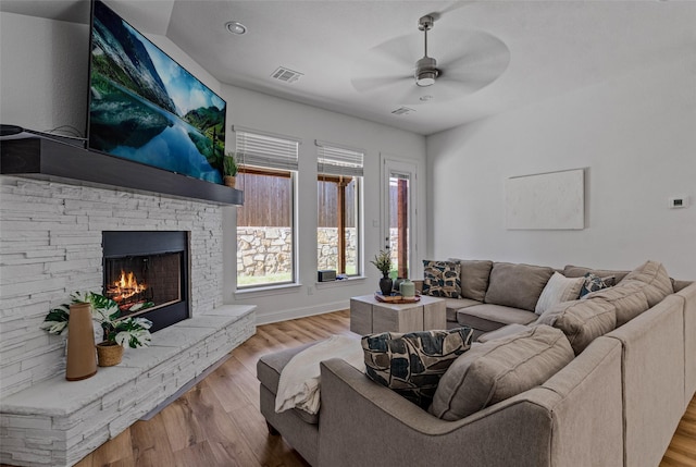 living area with baseboards, visible vents, ceiling fan, wood finished floors, and a fireplace