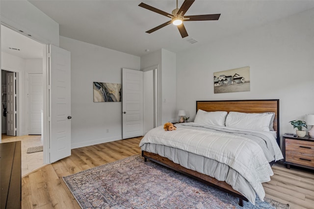 bedroom with ceiling fan, light wood-type flooring, visible vents, and baseboards