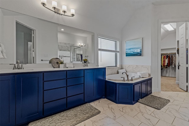 full bath with double vanity, lofted ceiling, marble finish floor, a walk in closet, and a bath