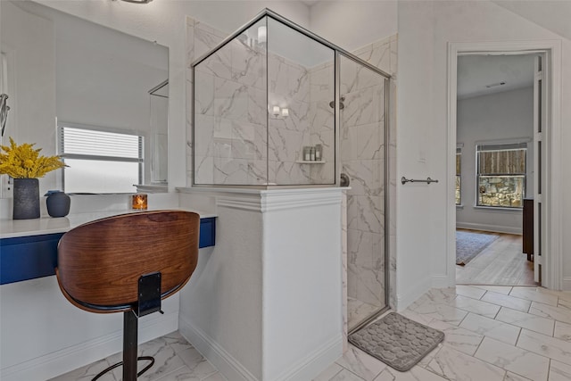 full bath featuring marble finish floor, a stall shower, and plenty of natural light