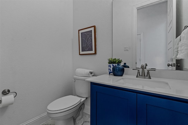 bathroom with marble finish floor, vanity, toilet, and baseboards