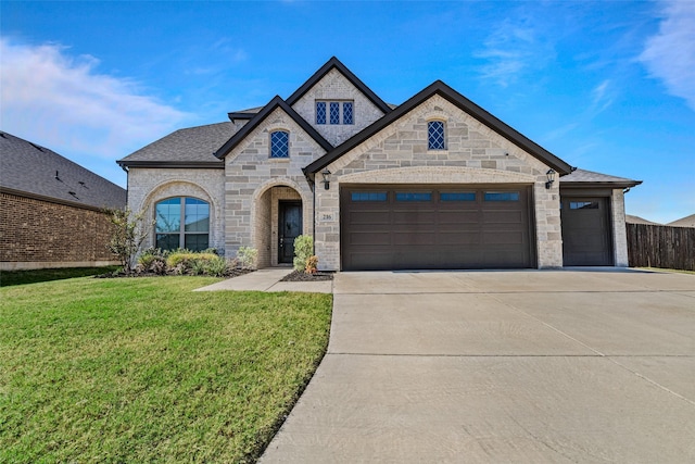 french provincial home with an attached garage, driveway, a shingled roof, and a front yard