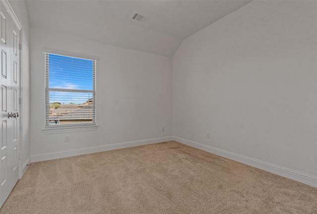 unfurnished room featuring light carpet, baseboards, visible vents, and vaulted ceiling