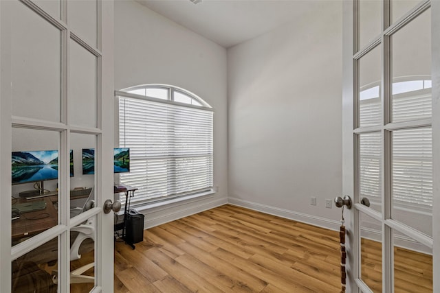 interior space featuring light wood-type flooring, french doors, a healthy amount of sunlight, and baseboards