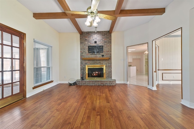 unfurnished living room with a fireplace, baseboards, hardwood / wood-style floors, and beamed ceiling